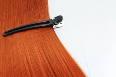 Güzel kırmızı saç ve barrette ışık arka plan, closeup. Metin için alan