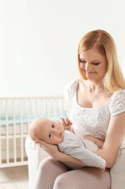 Evde koltukta oturan bebeği ile mutlu anne