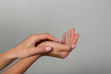 Gri arka planda ıslak elleri olan bir kadın, yakın plan. Spa tedavisi