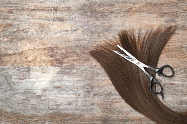 Düz kahverengi saçlı kompozisyon yatıyordu, inceltme makas ve ahşap arka plan üzerinde metin için alan. Kuaför hizmeti