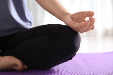 Kadın içeride yoga yapıyor, yakın plan.