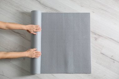 Kadın yoga minderini yerde yuvarlıyor, üst manzara. Metin için boşluk