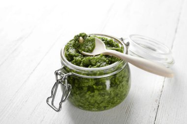 Tahta masa üzerinde kaşık ile pesto sos Kavanoz
