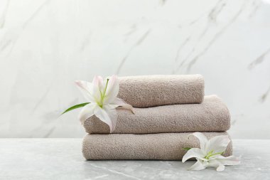 Açık arka plan karşı gri masa üzerinde çiçek ile taze havlu Yığını