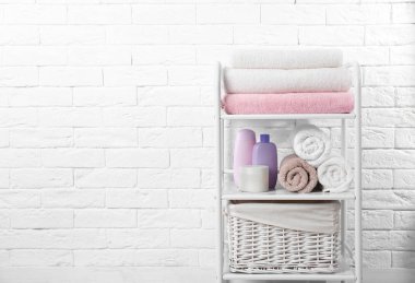 Temiz havlu ve tuğla duvar ayakın banyo malzemeleri ile raf ünitesi. Metin için alan