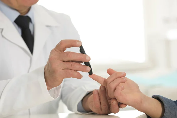 Doctor tomando la muestra de sangre del paciente con lapicera de lanceta en el hospital, primer plano. Control de la diabetes — Foto de Stock