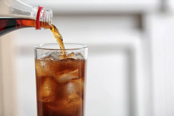 Menuang cola dari botol ke kaca pada latar belakang kabur, closeup. Ruang untuk teks — Stok Foto