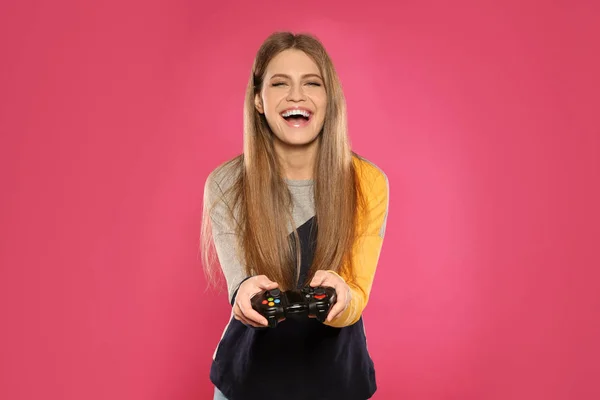 Mujer joven emocional jugando videojuegos con controlador en el fondo de color —  Fotos de Stock