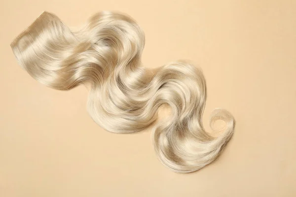 Serrure de cheveux blonds ondulés sur fond de couleur, vue de dessus — Photo