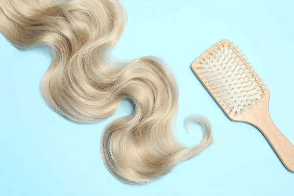 Bloqueio de cabelo ondulado loiro e escova no fundo de cor, flat lay — Fotografia de Stock