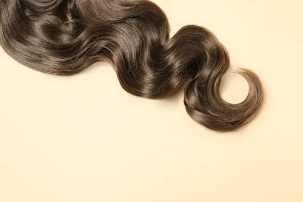 Mechón de pelo castaño ondulado sobre fondo de color, vista superior. Espacio para texto — Foto de Stock