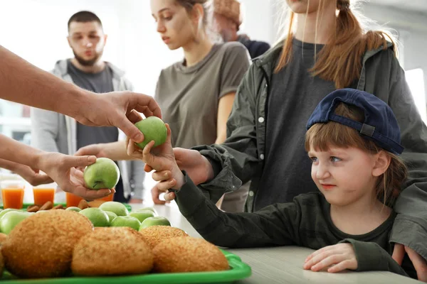 Voluntario dando manzana a la pobre chica en el interior — Foto de Stock