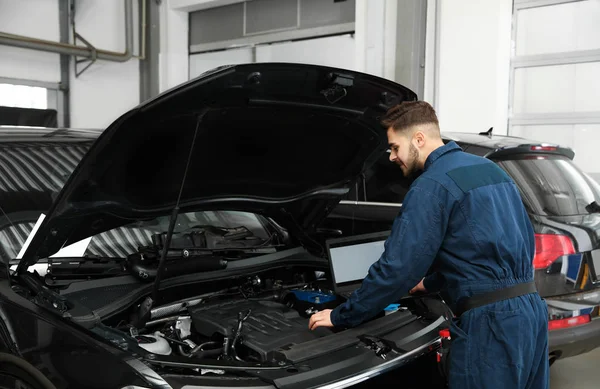 Técnico verificando carro com laptop na oficina de reparação de automóveis — Fotografia de Stock