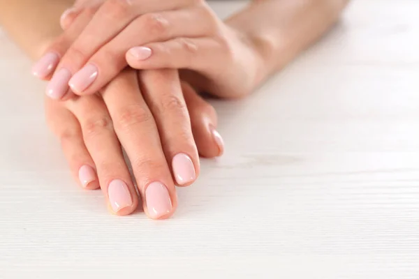 Vista de cerca de la mujer con hermosas manos en la mesa de madera blanca, espacio para el texto. Tratamiento de spa — Foto de Stock