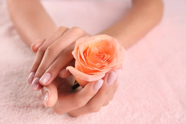 Vista de cerca de hermosas manos femeninas con rosa en la toalla, espacio para el texto. Tratamiento de spa — Foto de Stock