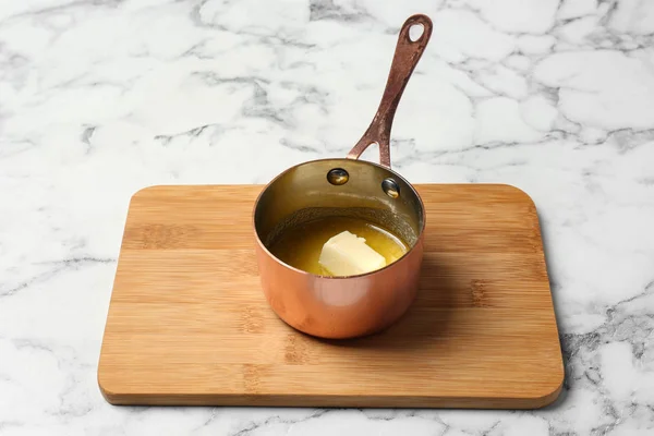 Cazuela con mantequilla derretida sobre mesa de mármol — Foto de Stock