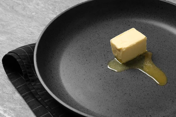 Fritovací pánev s tavicím máslem na šedý stůl, zaostřená — Stock fotografie