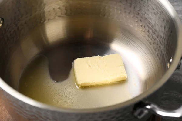 Pedaço de manteiga derretida em vaso, close-up — Fotografia de Stock