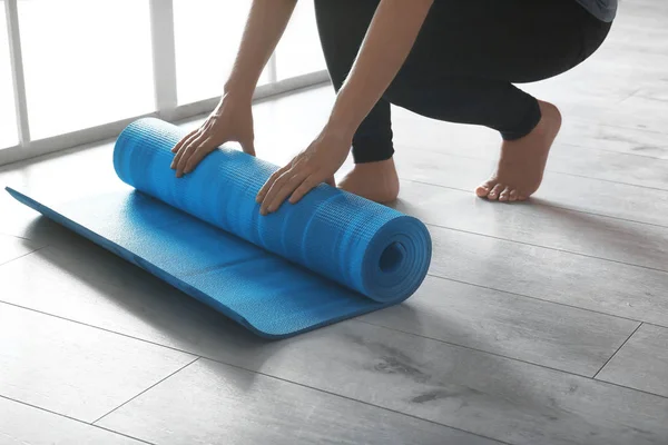 Woman rolling yoga mat on floor indoors, closeup — Stock Photo, Image