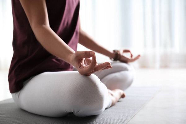 Woman practicing yoga on floor indoors, closeup. Space for text