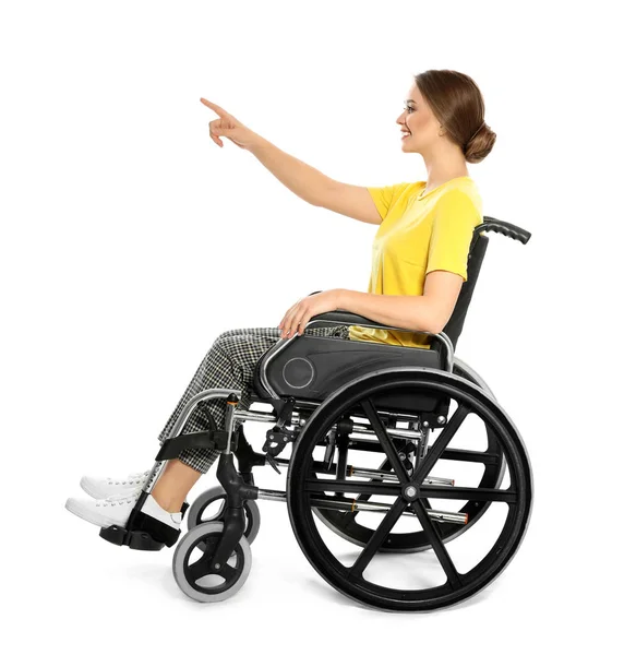 Mujer joven en silla de ruedas señalando algo aislado en blanco — Foto de Stock