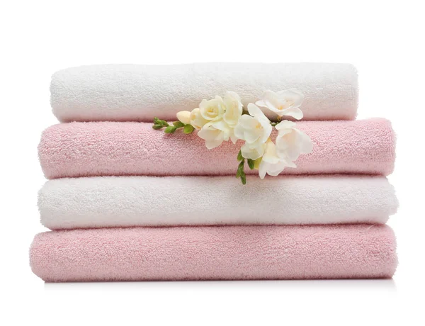 Montón de toallas limpias plegadas con flores sobre fondo blanco — Foto de Stock