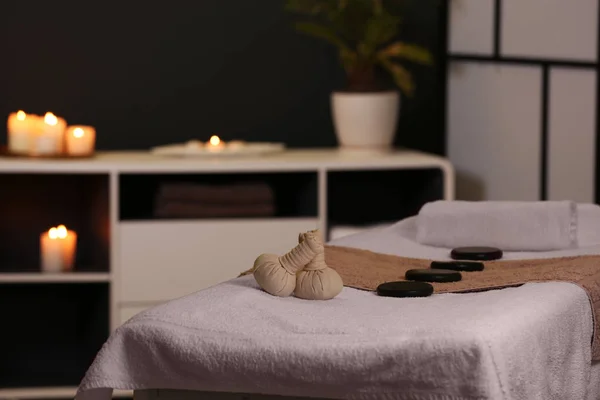 Herbal compresses and stones on massage table in spa salon — Stock Photo, Image