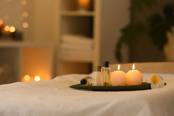 Kosmetyki i płonące świece na stole do masażu w salonie Spa, miejsce na tekst — Zdjęcie stockowe