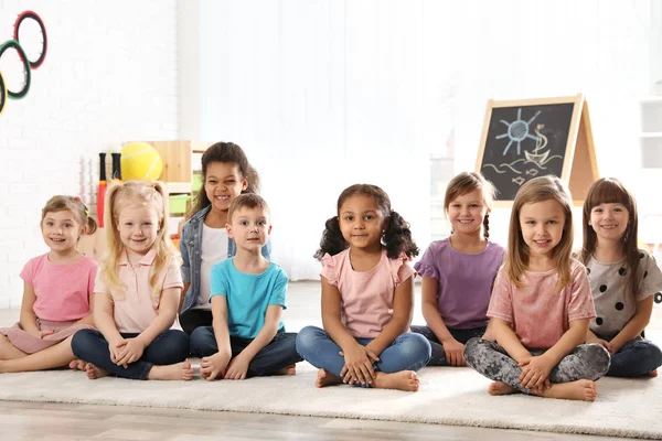 Grupa cute małe dzieci siedzi na podłodze w pomieszczeniu. Przedszkole zabawy — Zdjęcie stockowe