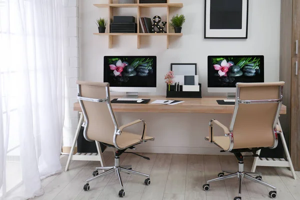 Moderno lugar de trabajo con escritorio grande y computadoras en la habitación. Interior con estilo — Foto de Stock