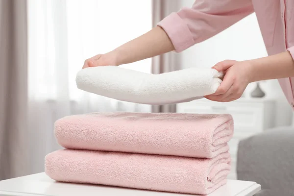 Mujer apilando toallas limpias en la mesa en la habitación —  Fotos de Stock