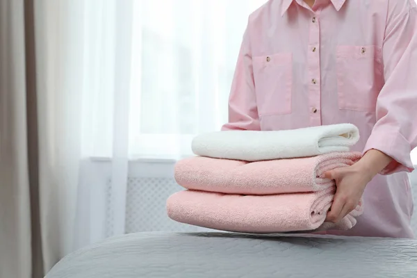 Kvinnan lägger en hög rena handdukar på sängen. Plats för text — Stockfoto