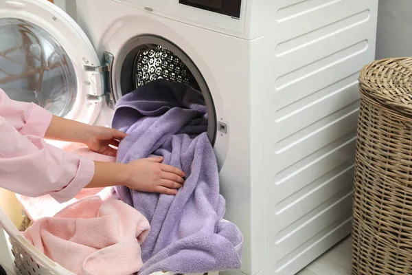 Женщина вынимает полотенца из стиральной машины в прачечной — стоковое фото