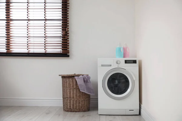 Máquina de lavar roupa moderna e cesta de lavanderia dentro de casa — Fotografia de Stock