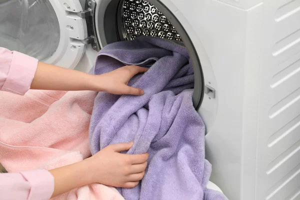 Egy nő törölközőt vesz ki a mosógépből a mosókonyhában. — Stock Fotó
