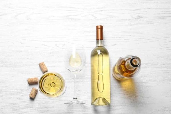 Glas och flaskor med vitt vin på trä bakgrund, Flat Lay — Stockfoto