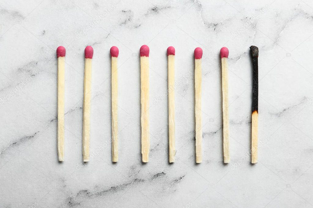 Used match among whole ones on marble background, flat lay. Psychological burnout concept