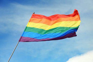 Parlak gökkuşağı gay bayrağı mavi gökyüzüne karşı çırpınan. Lgbt topluluğu