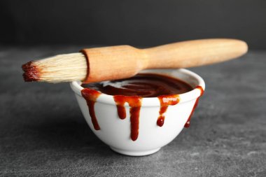 Gri masada barbekü sosu ve fırça ile Kase