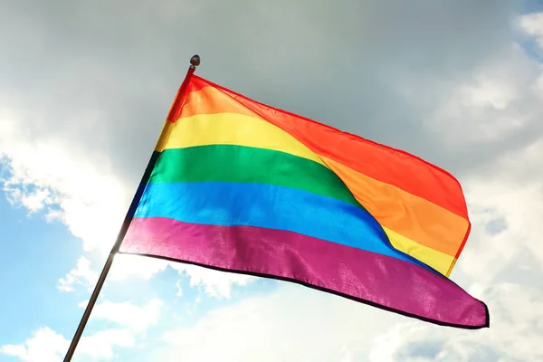 Bright rainbow gay flag revoloteando contra el cielo azul. Comunidad LGBT — Foto de Stock