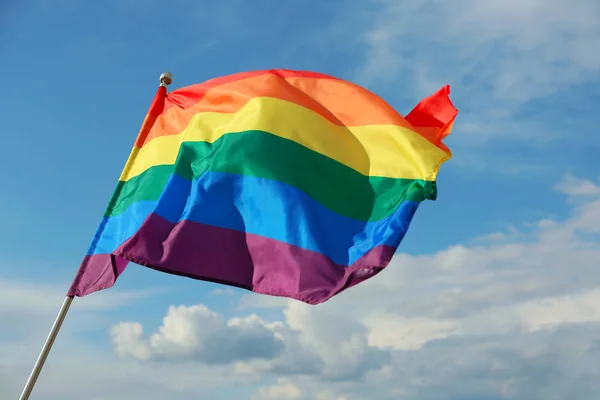 Bright rainbow gay flag fluttering against blue sky. LGBT community