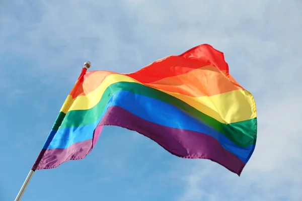 Bright rainbow gay flag revoloteando contra el cielo azul. Comunidad LGBT — Foto de Stock