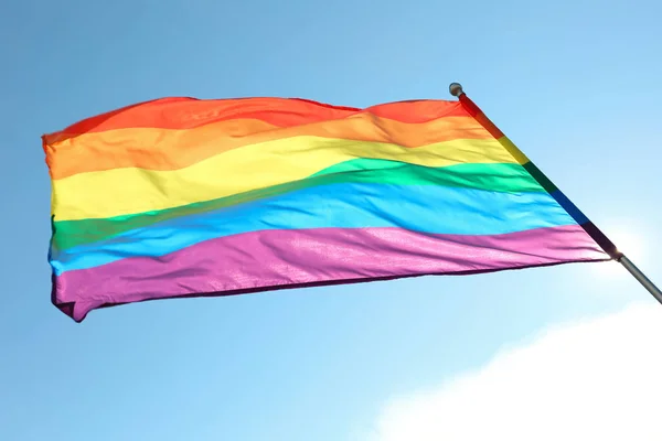 Яркий радужный гей-флаг, развевающийся над синим небом, вид снизу. ЛГБТ-сообщество — стоковое фото