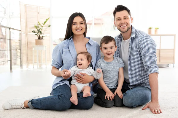 Lyckligt par med barn sitter på golvet hemma. Familjehelg — Stockfoto