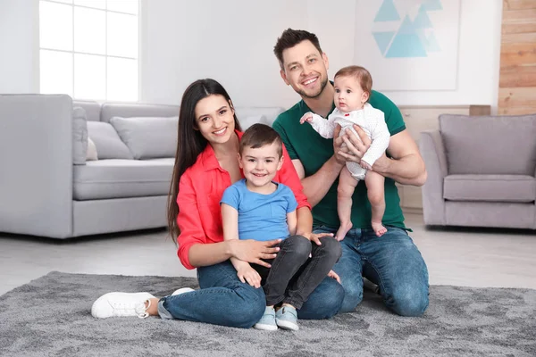 Glückliche Eltern und ihre niedlichen Kinder, die zu Hause auf dem Fußboden sitzen. Familienzeit — Stockfoto
