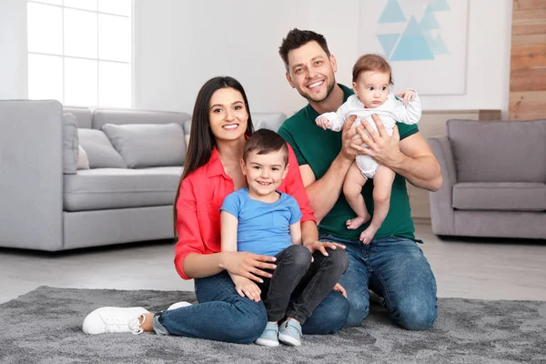 Gelukkige ouders en hun schattige kinderen zitten thuis op de vloer. Family time — Stockfoto