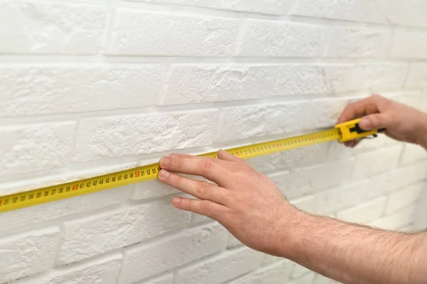 人测量室内砖墙，特写。构造工具 — 图库照片