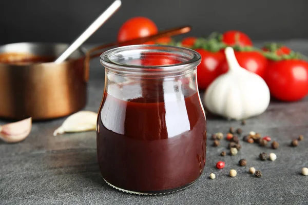 Komposition mit einem Glas Barbecue-Sauce auf grauem Tisch — Stockfoto