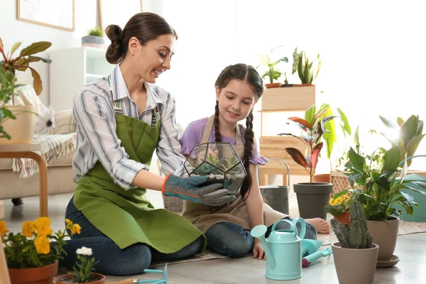 Mãe e filha cuidando de plantas no chão em casa — Fotografia de Stock