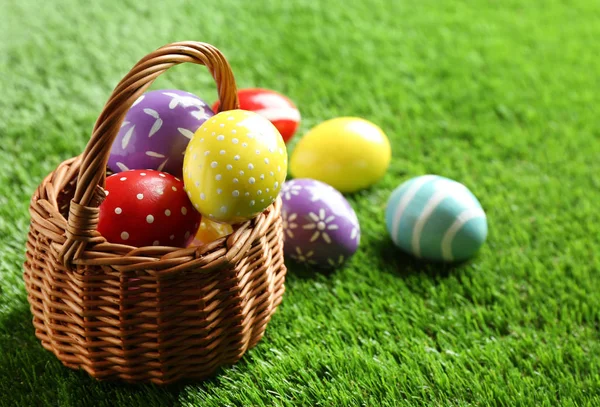 Cesta de mimbre con huevos de Pascua pintados sobre hierba verde, espacio para texto — Foto de Stock